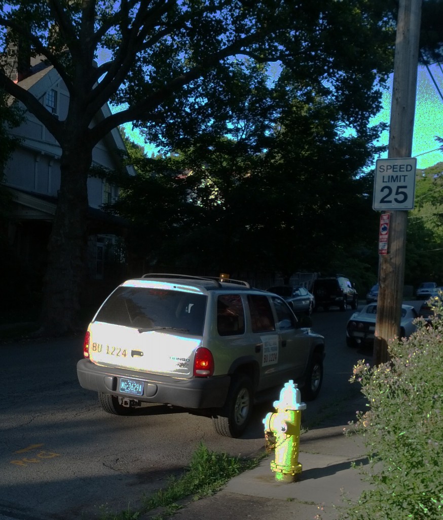 A SUV stopped at the side of a street.  It has signs about Allegheny County West Nile Virus control.